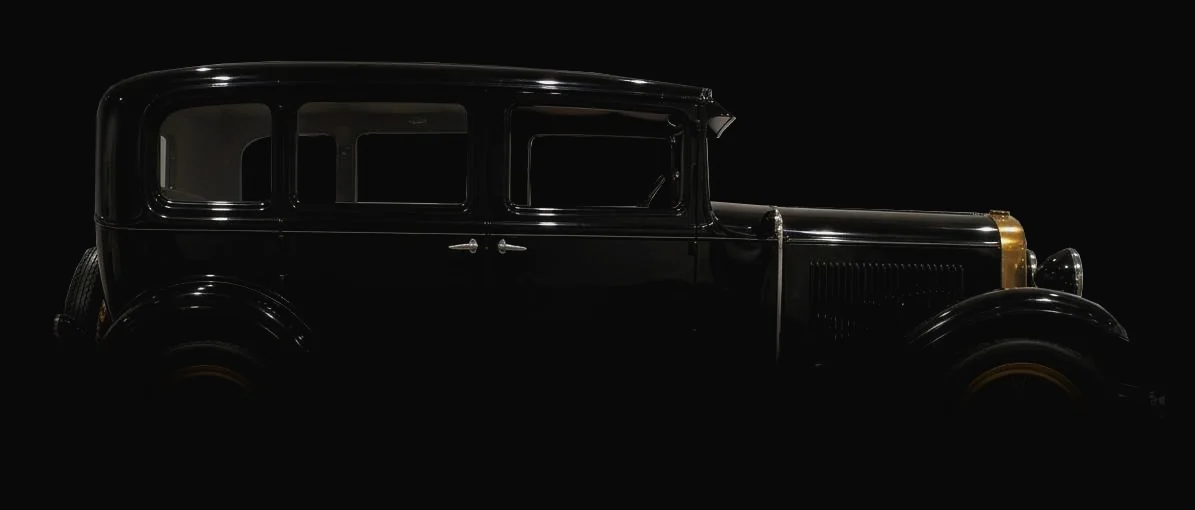 Berlina Abadal Continental de 1930, negra, vista lateral, fundiéndose en la oscuridad